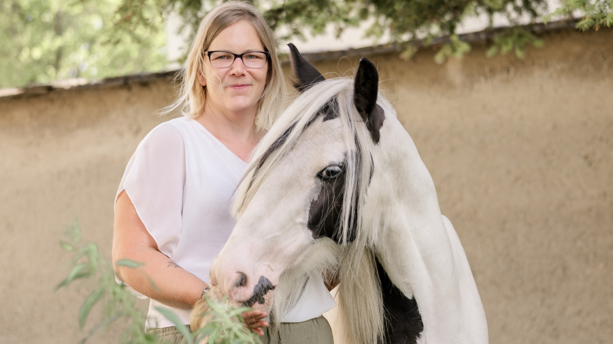 Krista, Gründerin von Krista's Mobile Tierbalance, mit einem schwarz-weißen Pferd